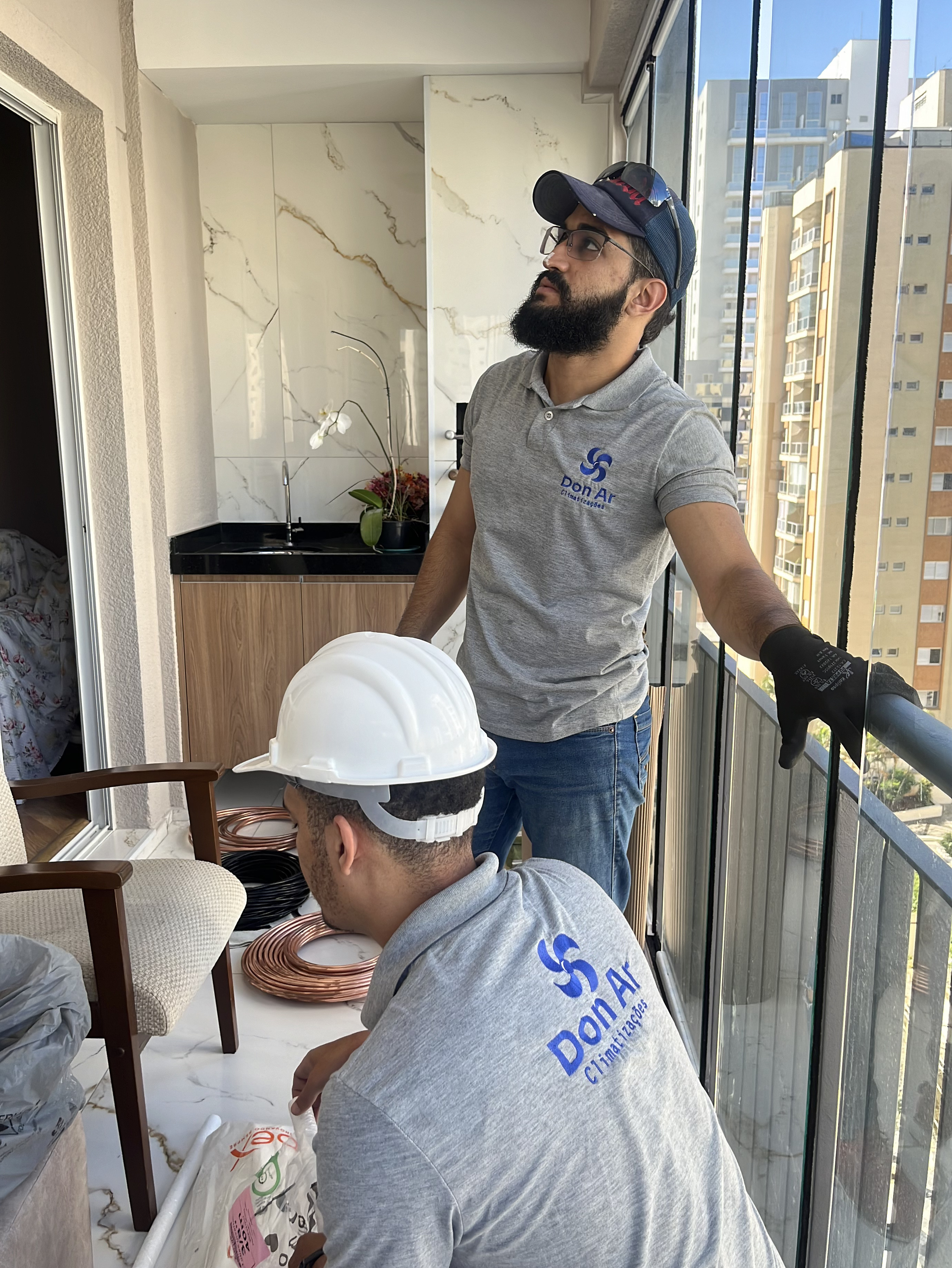 Profissionais da Don Ar preparando uma instalação de ar-condicionado em uma varanda residencial